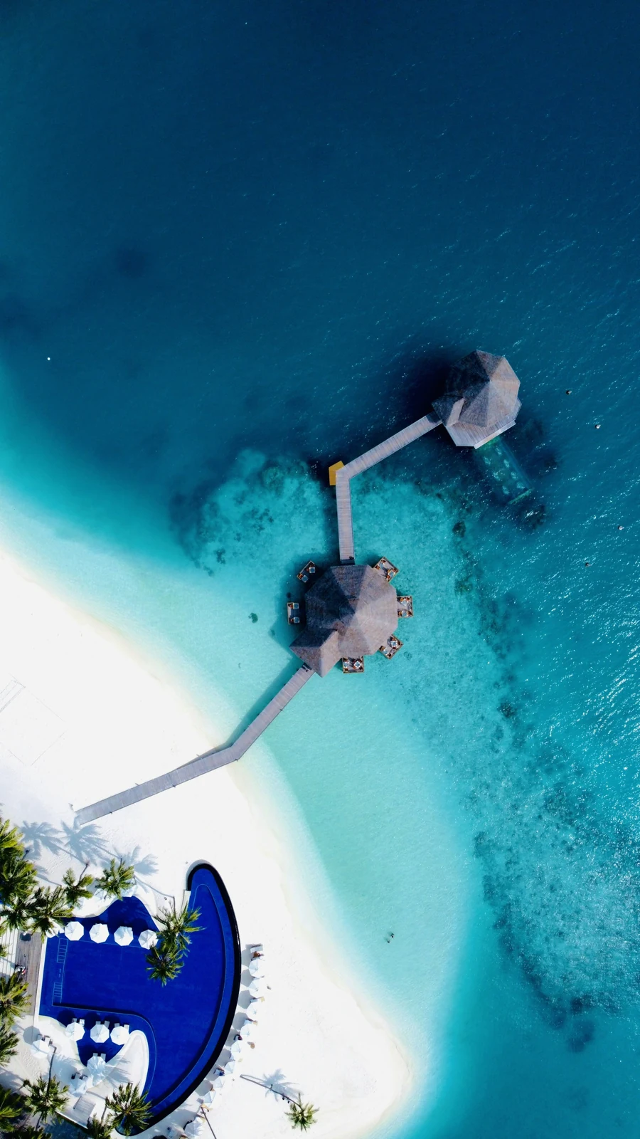 Пирс, постройки над водой, песчаный берег и бассейн Conrad Maldives Rangali Island, вид сверху